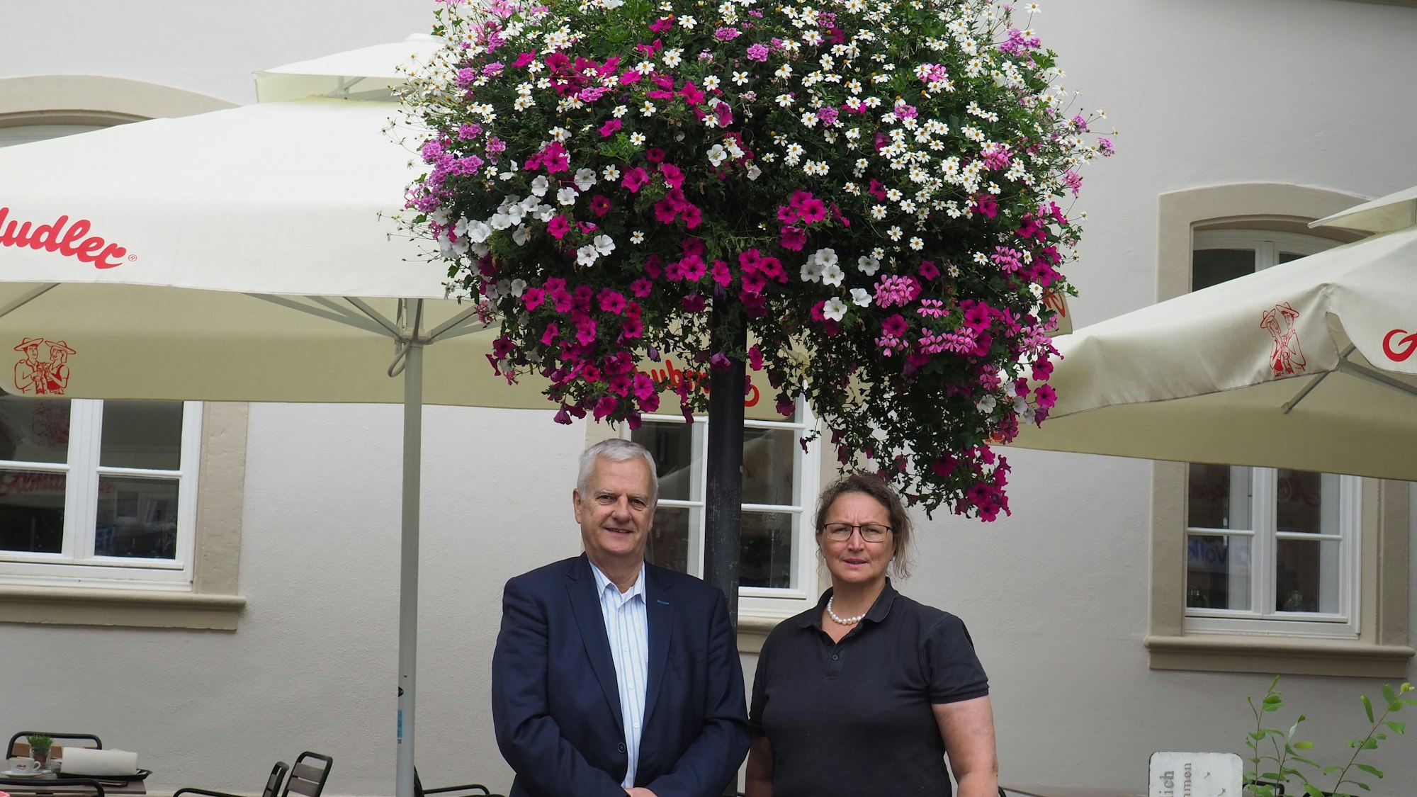 Ein Mann und eine Frau stehen unter einer üppigen Blumenampel.