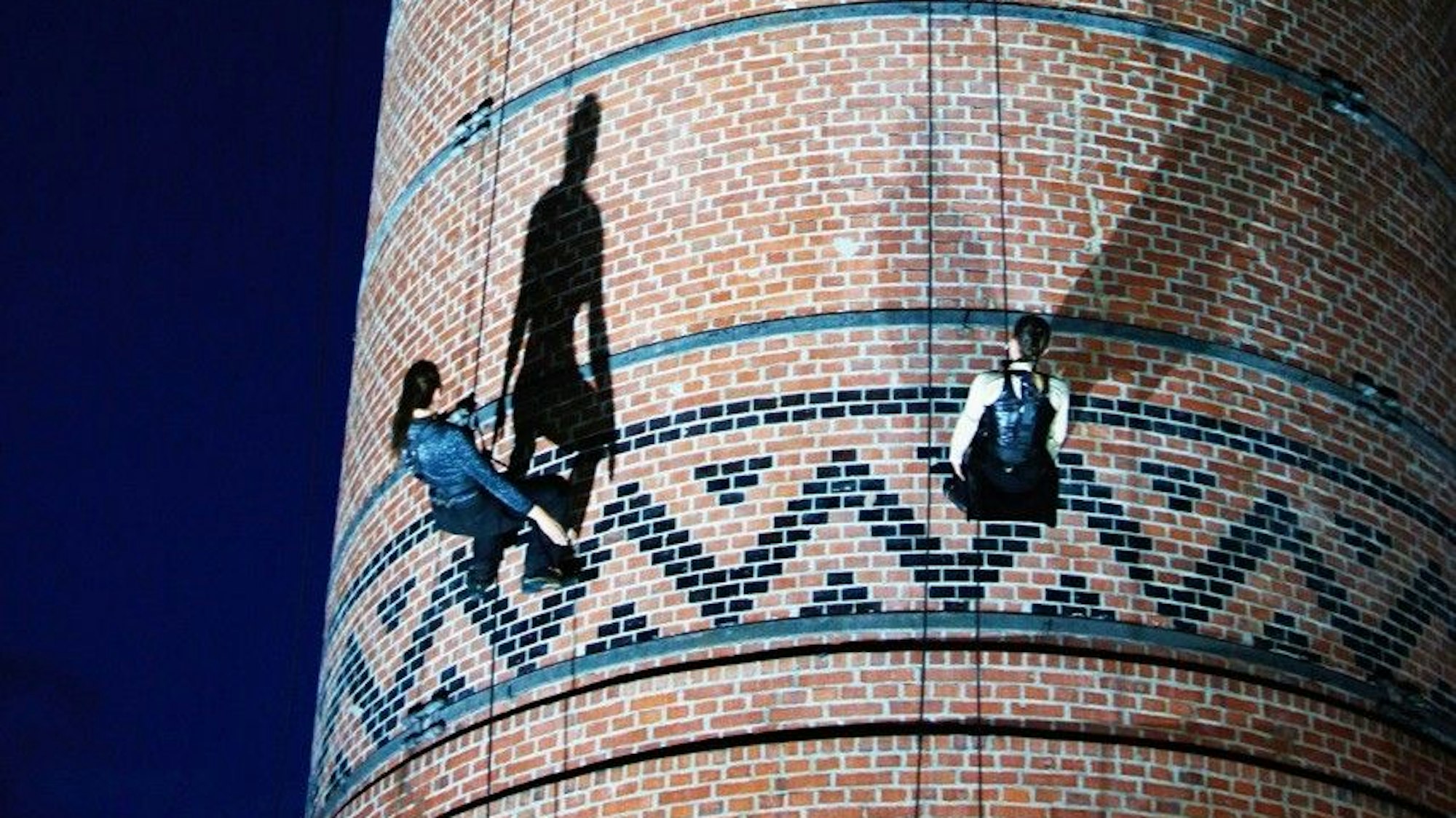 Zwei Leute hängen an Sicherheitsgurten an einem Schornstein.