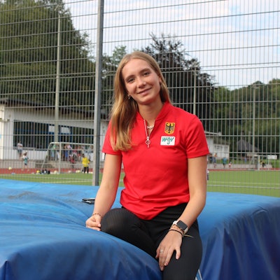 Zu sehen ist eine junge Frau auf einer Leichtathletik-Anlage.