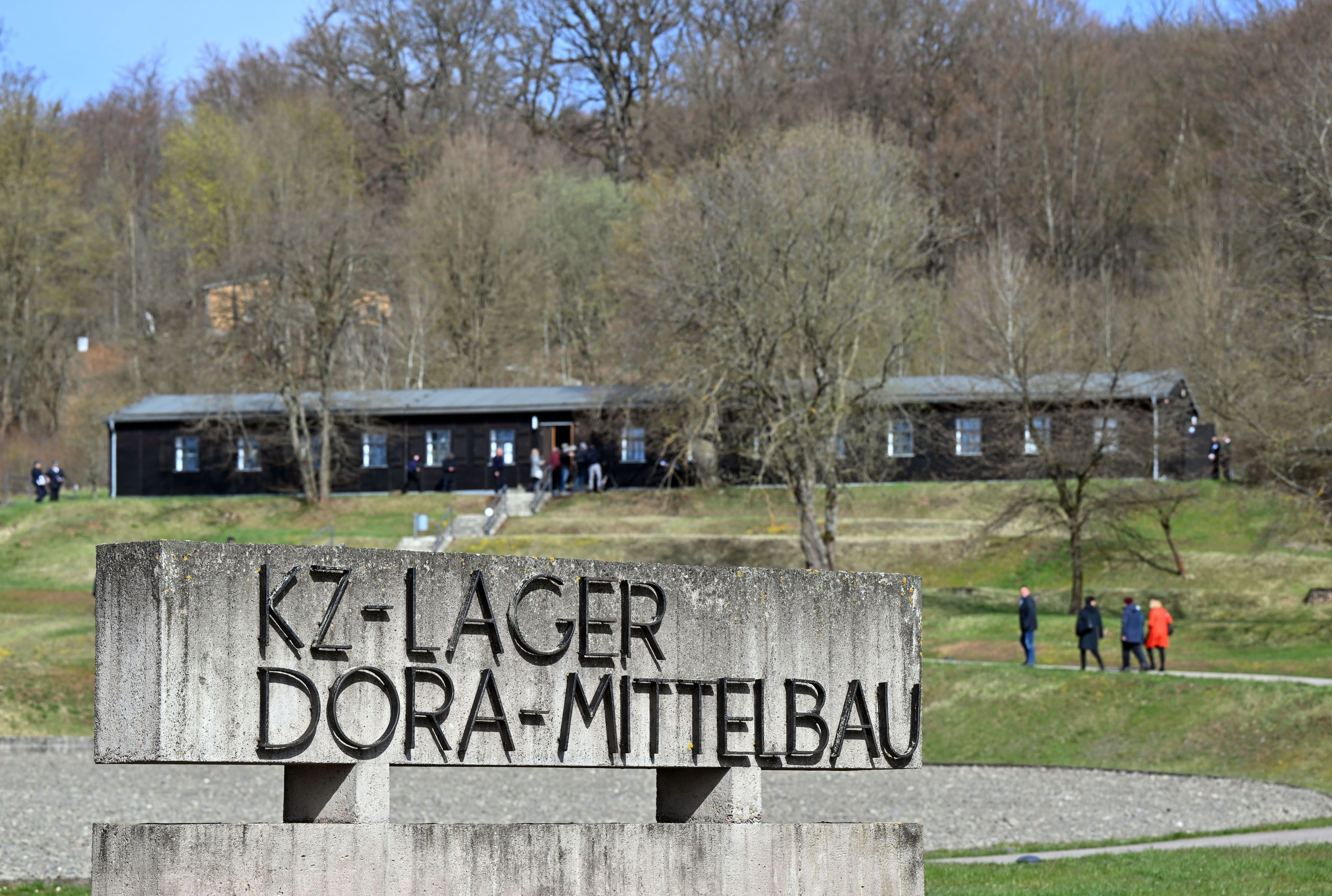 ARCHIV - 11.04.2022, Thüringen, Nordhausen: Besucher gehen zur Gedenkveranstaltung zum 77. Jahrestag der Befreiung des Konzentrationslagers Mittelbau-Dora durch US-Truppen am 11. April 1945. In Mittelbau-Dora, ursprünglich ein Außenlager des KZ Buchenwald, mussten zwischen 1943 und 1945 mehr als 60.000 Häftlinge aus fast allen Ländern Europas in Stollenanlagen Zwangsarbeit für die deutsche Rüstungsindustrie leisten.