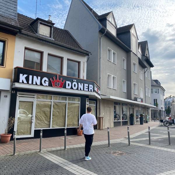 Das Bild zeigt eine Außenansicht des neuen Restaurants. Noch sind die Scheiben abgeklebt. Über der Tür steht die große Leuchtreklame mit dem Schriftzug King of Döner.