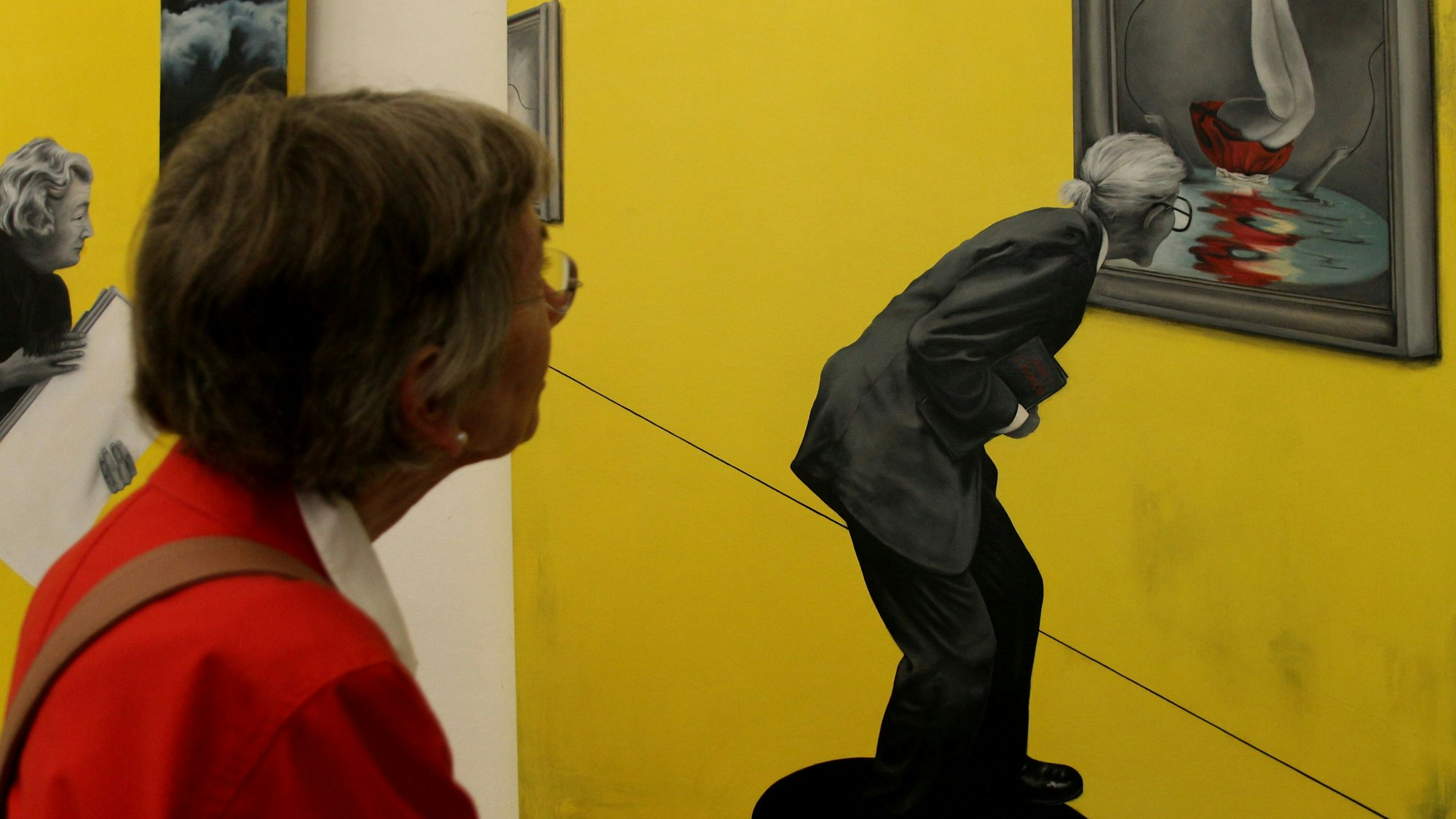 Eine Frau guckt sich ein Bild, auf dem ein Mann zu sehen ist, der ein Bild anguckt.