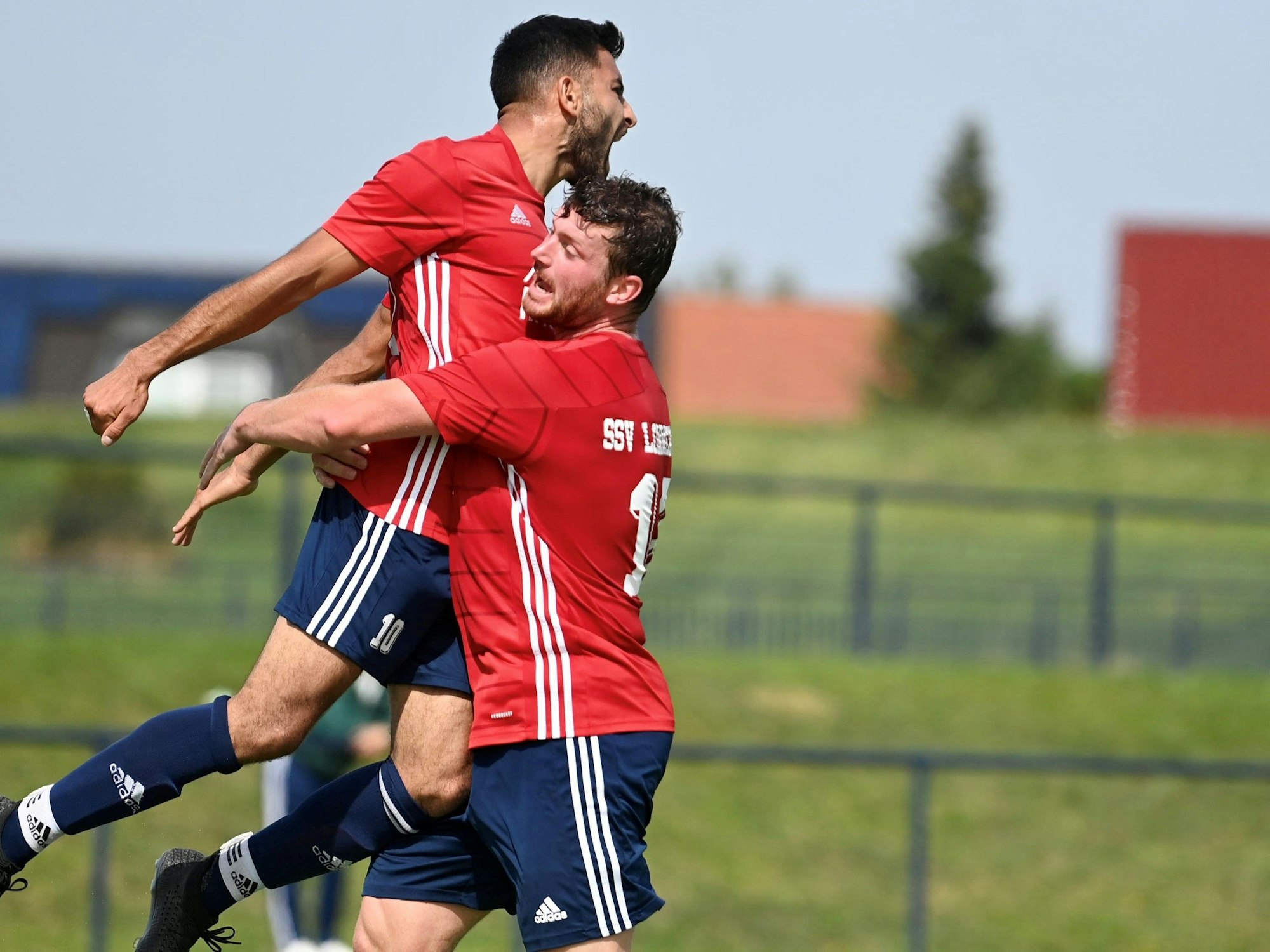 Ein Fußballspieler springt einem Teamkollegen jubelnd in die Arme.