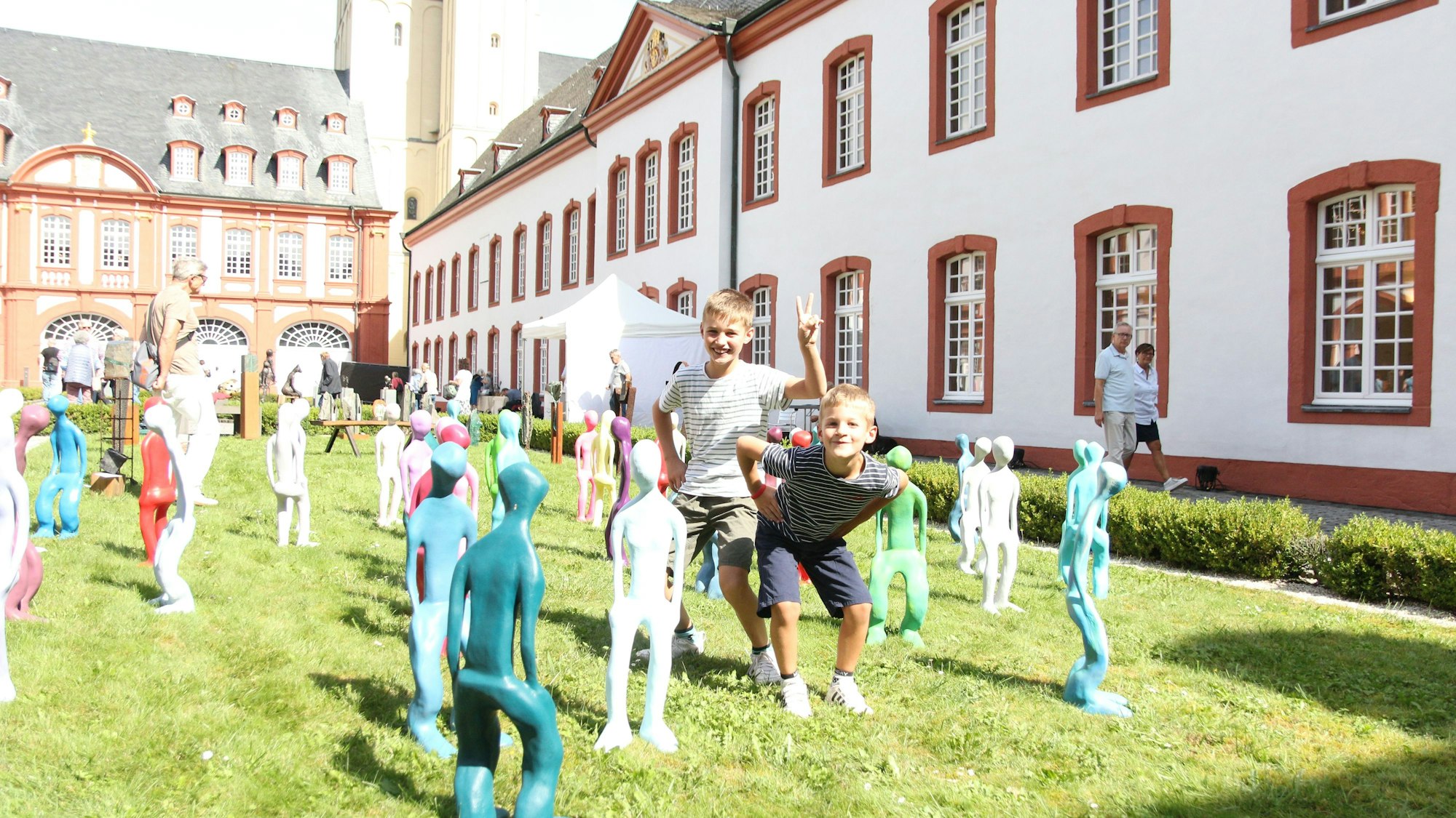 Zwei Jungs stehen zwischen bunten Skulpturen.