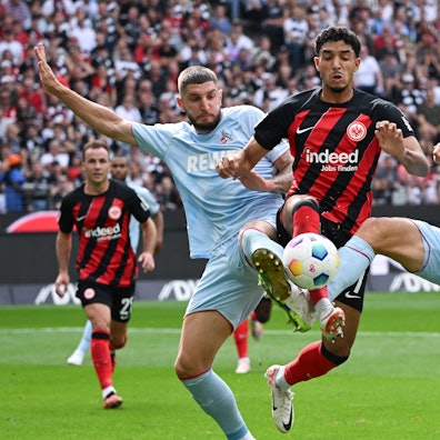 Frankfurts Omar Marmoush (M) und die Kölner Jeff Chabot (l) und Timo Hübers kämpfen um den Ball.