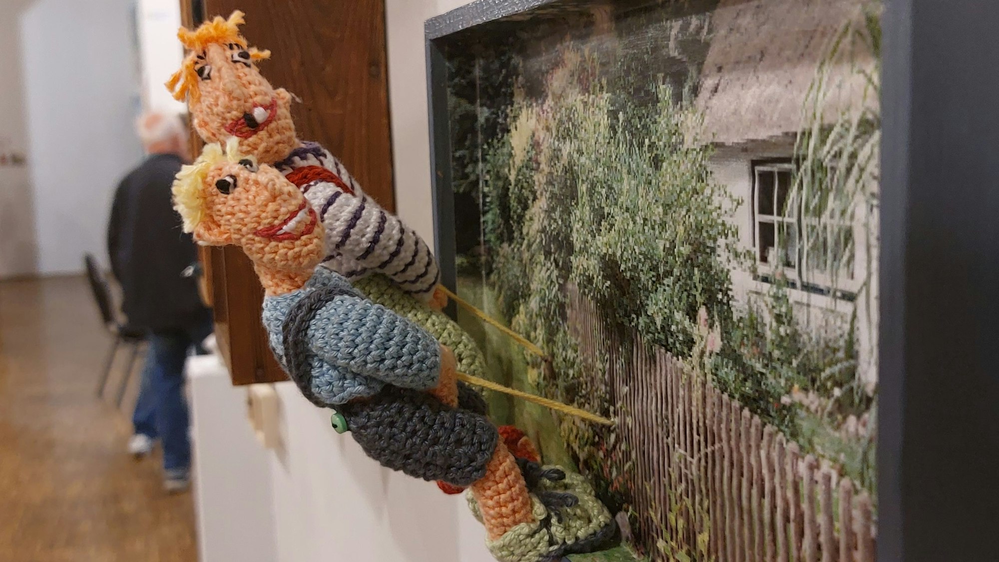 Zwei gehäkelte Jungs pieseln an einen Gartenzaun.