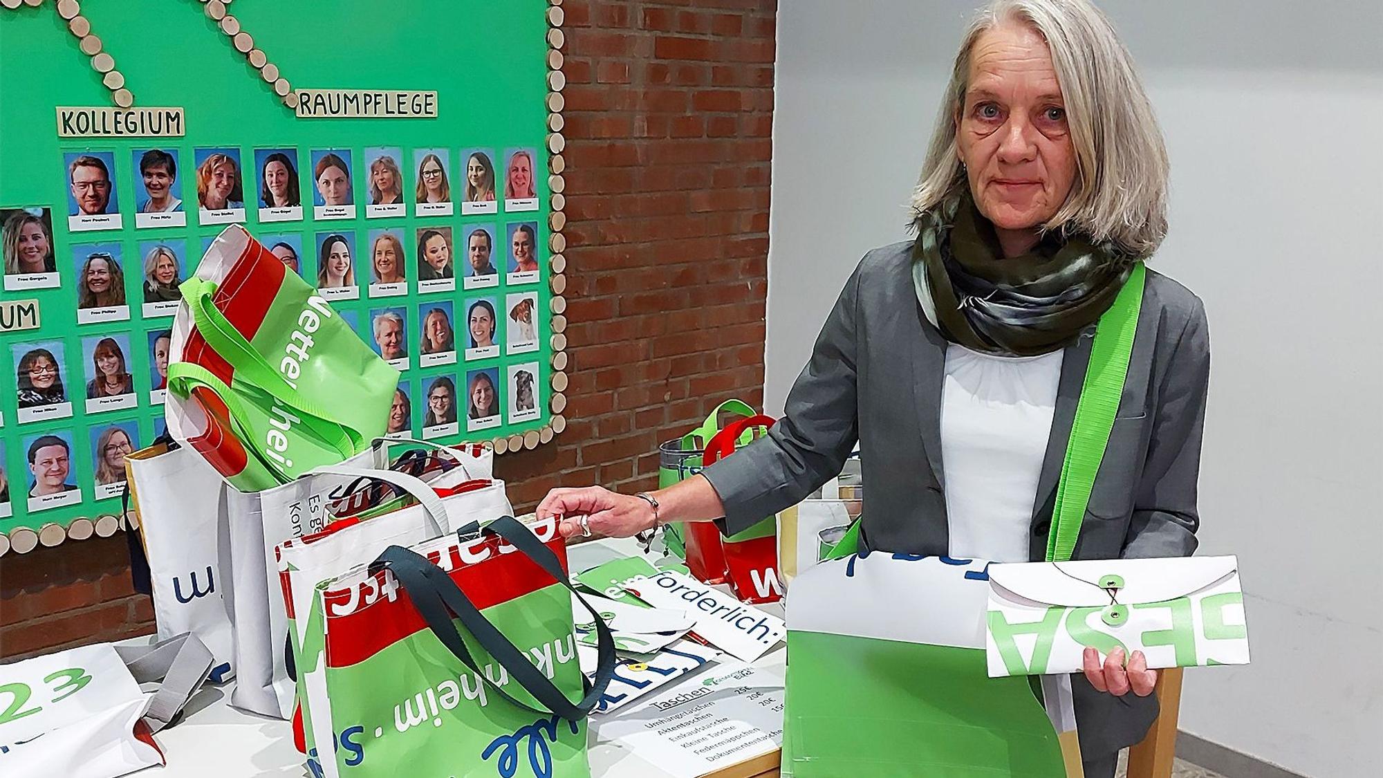 Elisabeth Weißkopf zeigt die umweltfreundlichen Artikel, die aus alten Plakaten der Gesamtschule Eifel hergestellt wurden.