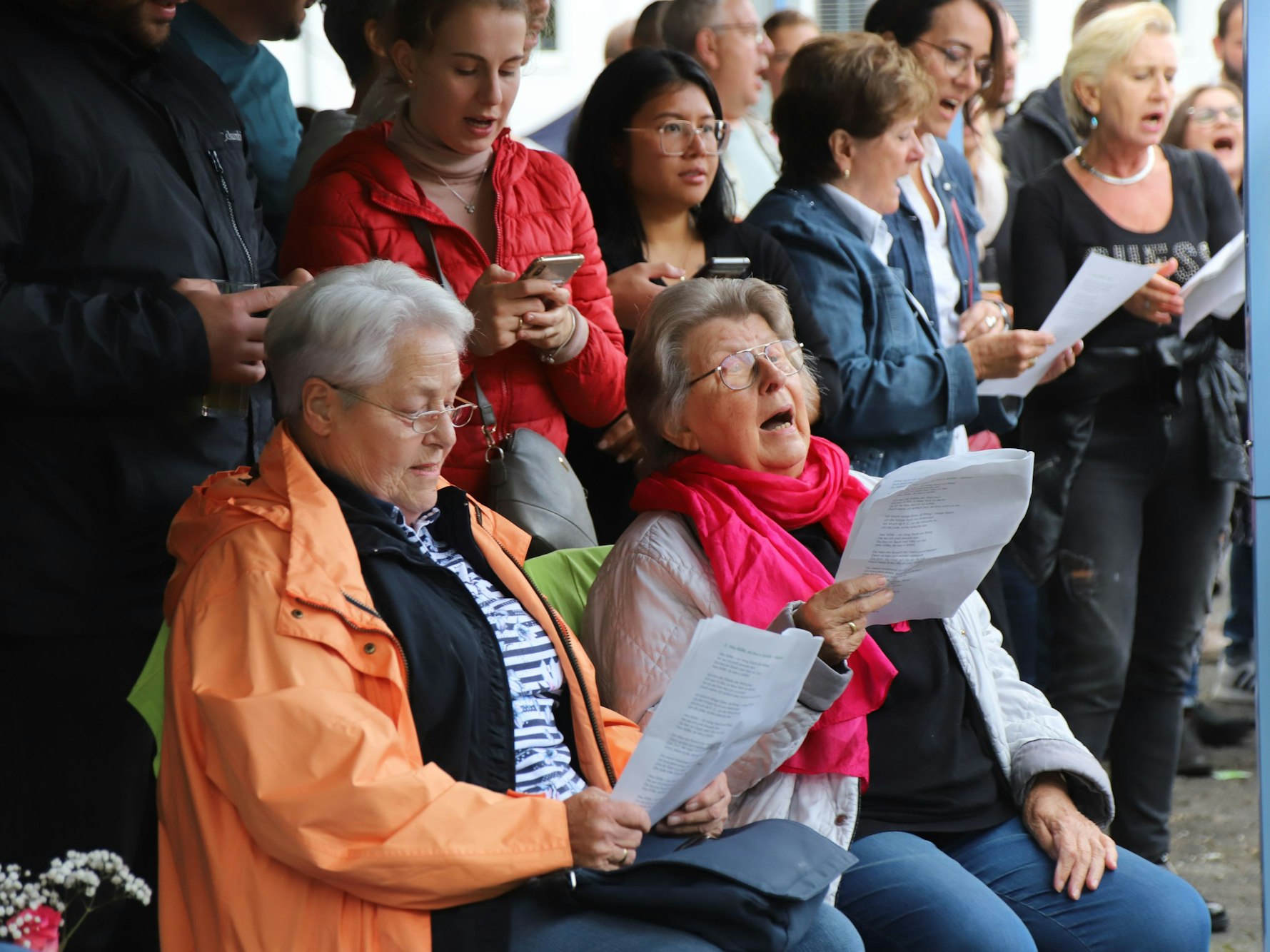Die Besucher des Mitsingkonzerts haben Textblätter in den Händen und singen die Lieder mit.