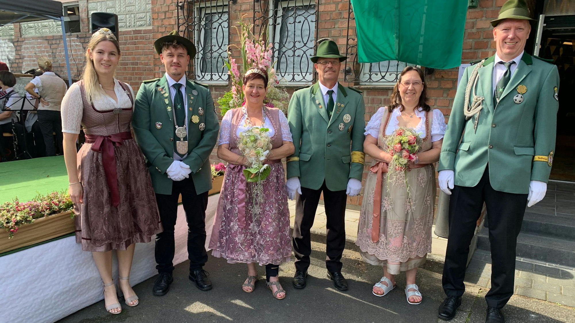 Die neuen Würdenträger präsentieren sich in Uniformen vor dem Schützenhaus in Sankt Augustin-Niederpleis: Stadtkönigin Robin Sorembe, Stadtkönig Dominik Reichelt, Königin Andrea II. (Grotzfeld), Prinzgemahl Dieter Grotzfeld, die Adjutant Alexandra Harmke und Dominik Harmke (von links nach rechts).