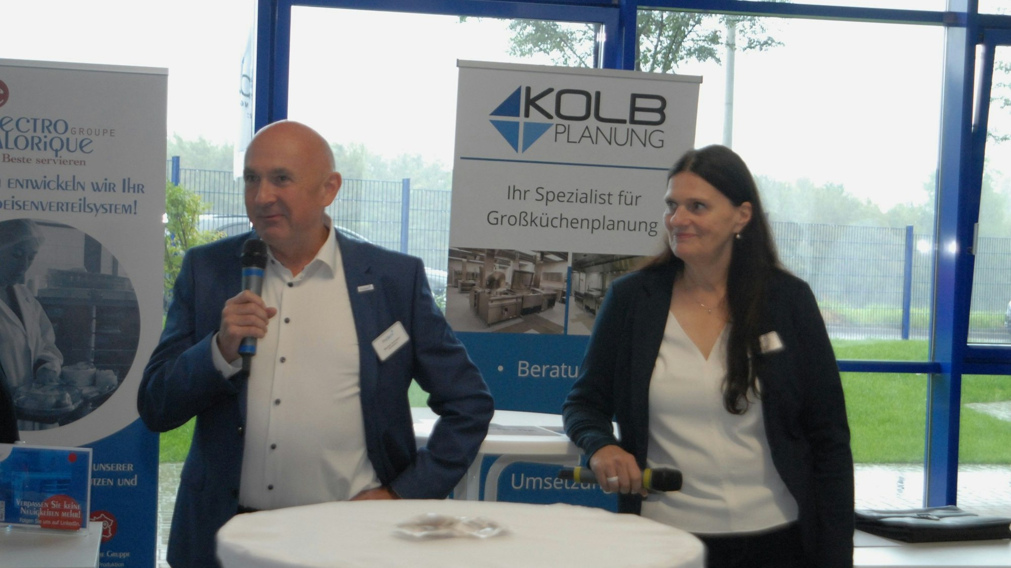 Ein Mann und eine Frau halten Mikrofone in den Händen.