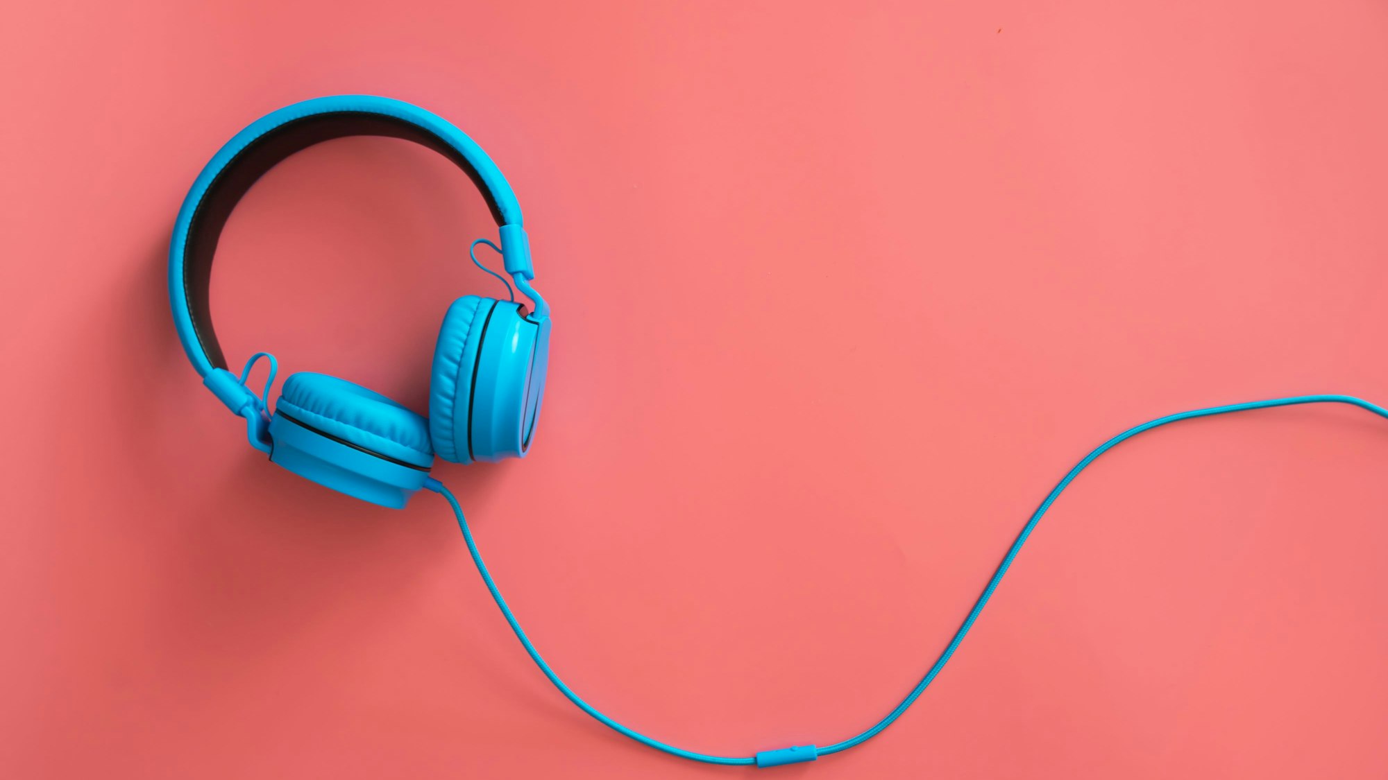 Blaue Kopfhörer liegen auf rotem Untergrund