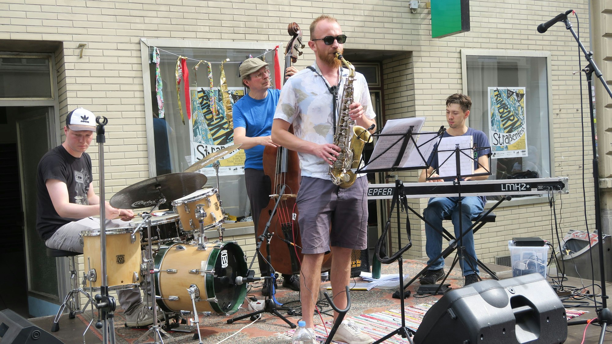 Musiker stehen auf einer kleinen Bühne.