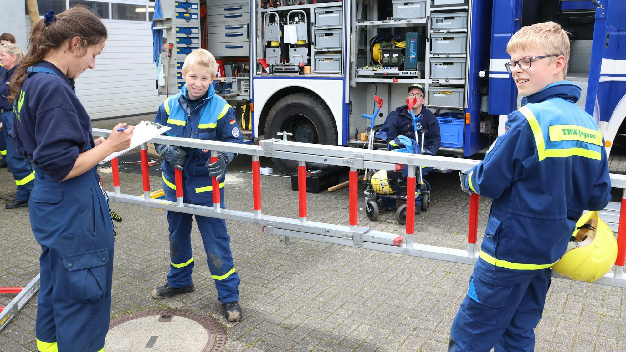 Kritisch und sorgfältig prüft Laura Willach von der Bezirksjugend des Technischen Hilfswerks in Waldbröl die Arbeit von Leonard Bornträger (links) und Maximilian Thurau aus Bergneustadt. Soeben haben die beiden Jungs Leitern zusammengesteckt.