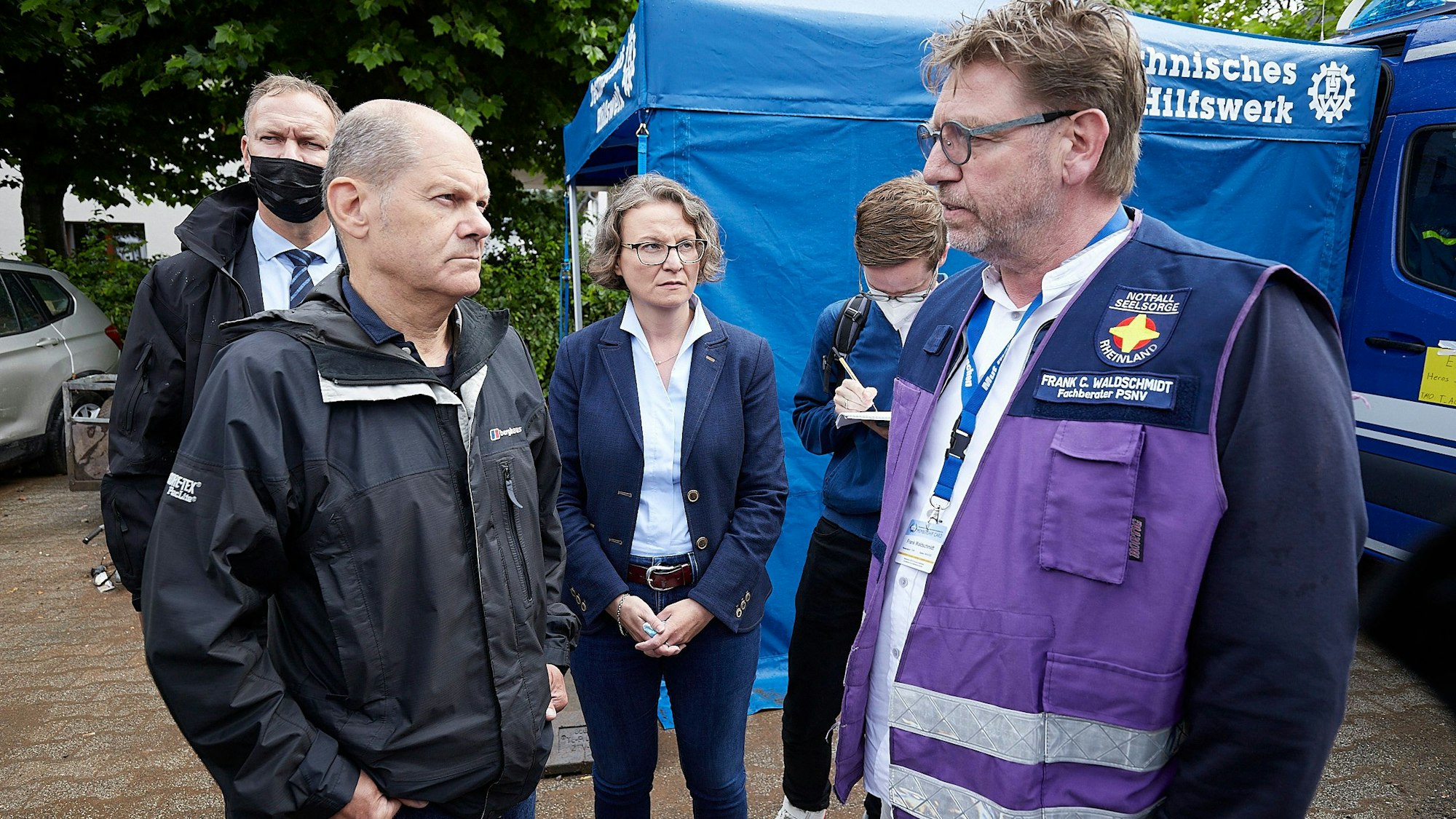 Olaf Scholz und Ina Scharrenbach sprechen mit Frank Waldschmidt. Im Hintergrund steht ein Zelt des Technischen Hilfswerks.