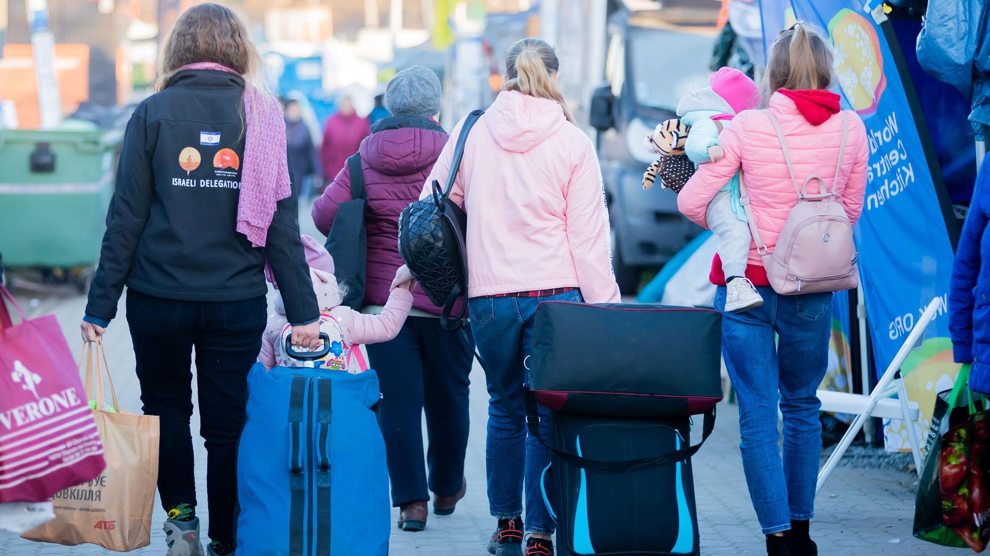 Frauen und Kinder, die aus der Ukraine geflohen sind, werden am Grenzübergang Medyka, kurz hinter der ukrainischen Grenze, auf polnischer Seite, von einer freiwilligen Helferin (l.) begleitet.