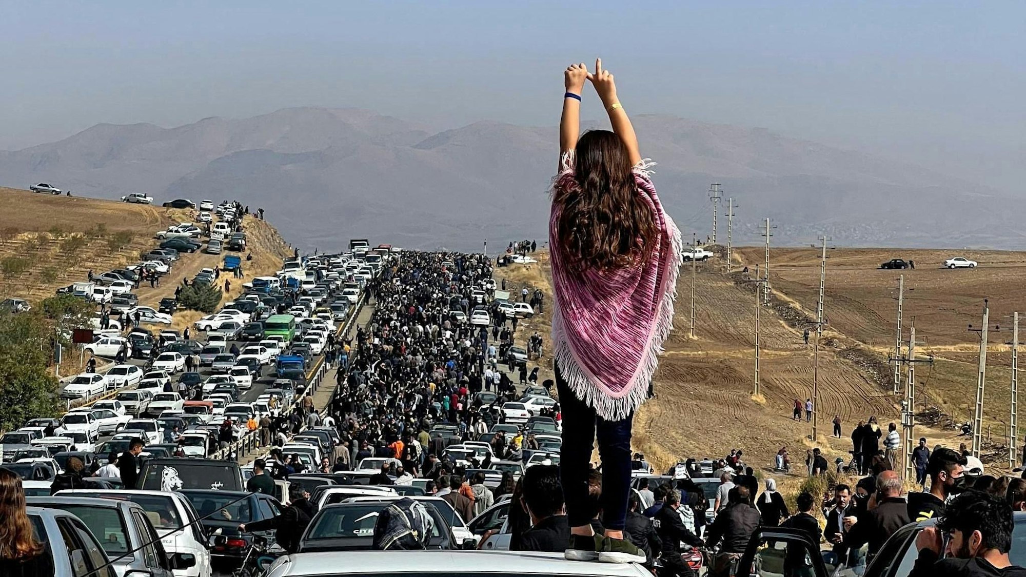 (FILES) This file UGC image posted on Twitter reportedly on October 26, 2022 shows an unveiled woman standing on top of a vehicle as thousands make their way towards Aichi cemetery in Saqez, Mahsa Amini's home town in the western Iranian province of Kurdistan, to mark 40 days since her death, defying heightened security measures as part of a bloody crackdown on women-led protests. - Mahsa Amini was an Iranian woman like any other, but she went down in history as one influential figure for her death on September 16 gave rise to a protest movement which, after six months, continues to affect the society.