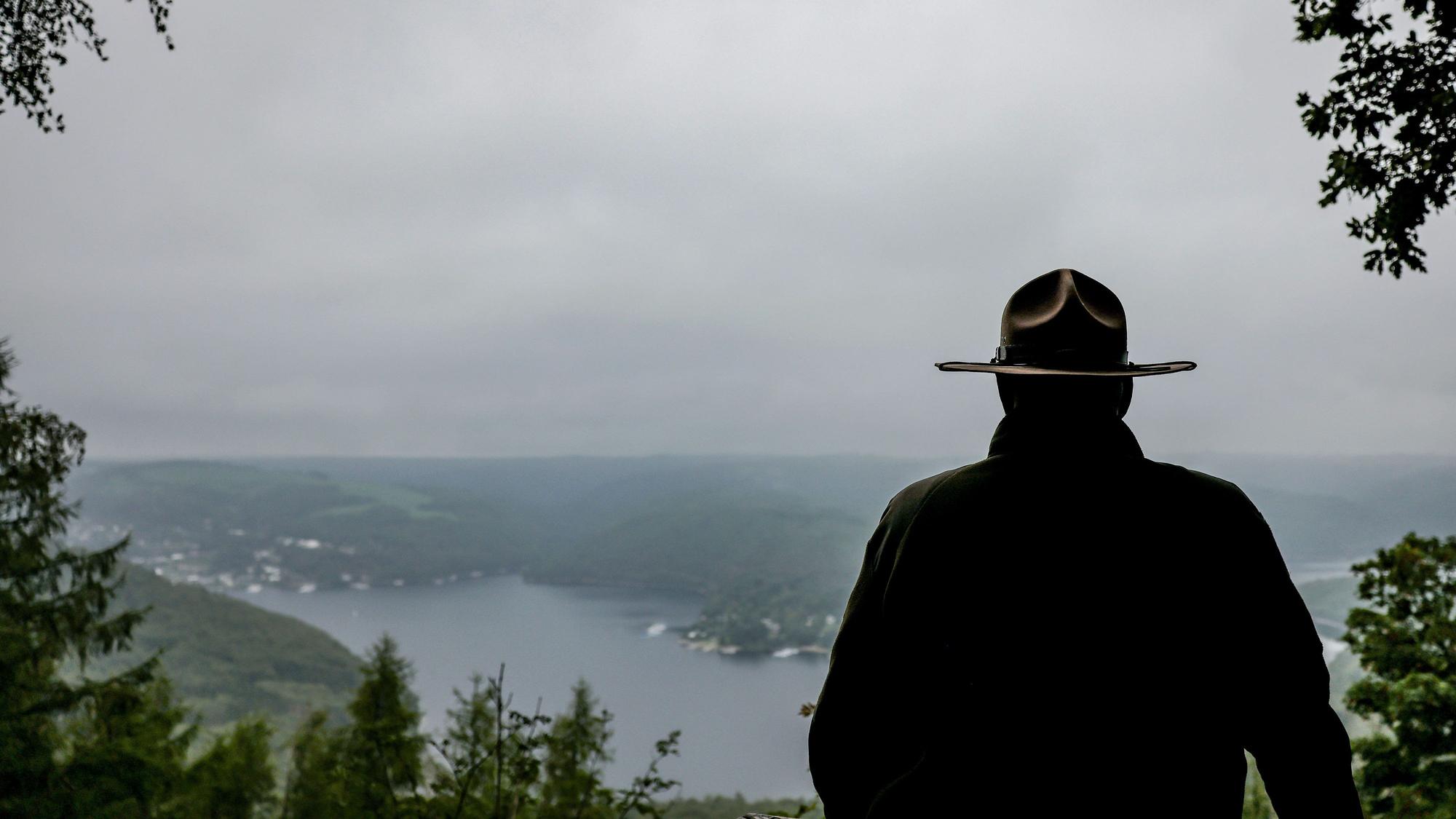 Ein Ranger steht im Nationalpark Eifel oberhalb des Urftsees an einer Lichtung.