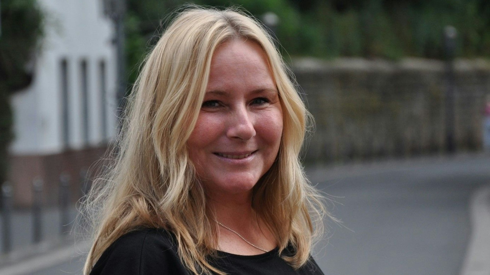 Elke Hörmann ist eine blonde Frau mit schulterlangen Haaren. Sie trägt ein schwarzes T-Shirt