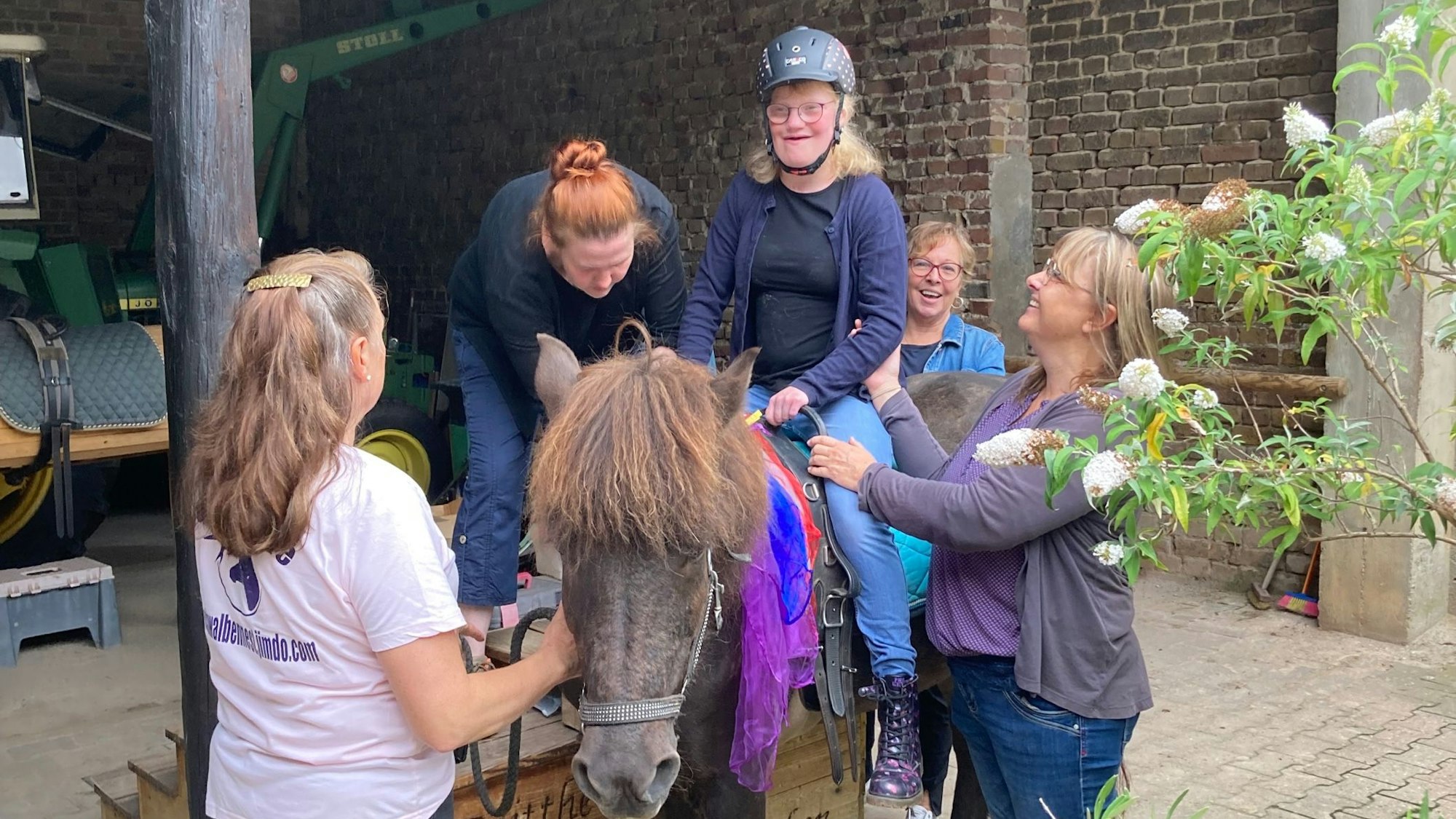 Die Schülerin sitzt auf einem Pferd, mehrere Frauen stehen drumherum.