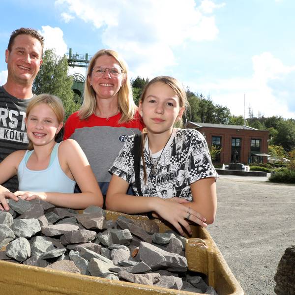 Eine Familie steht mit ihrer Gastschülerin aus Butscha hinter einem mit Schotter beladenen Förderwagen auf dem Lüderich.