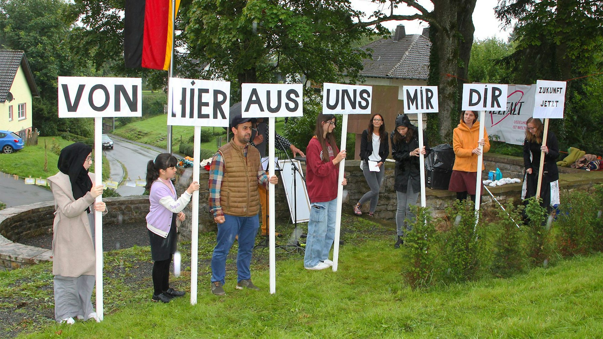 Einige Kinder und Jugendliche stehen in einer Reihe und halten Texttafeln in den Händen.