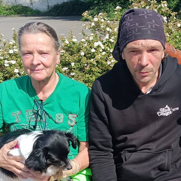 In der Mitte sitzt der Obdachlose Andreas Wüntenberg. Neben ihm sitzen zwei Frauen.
