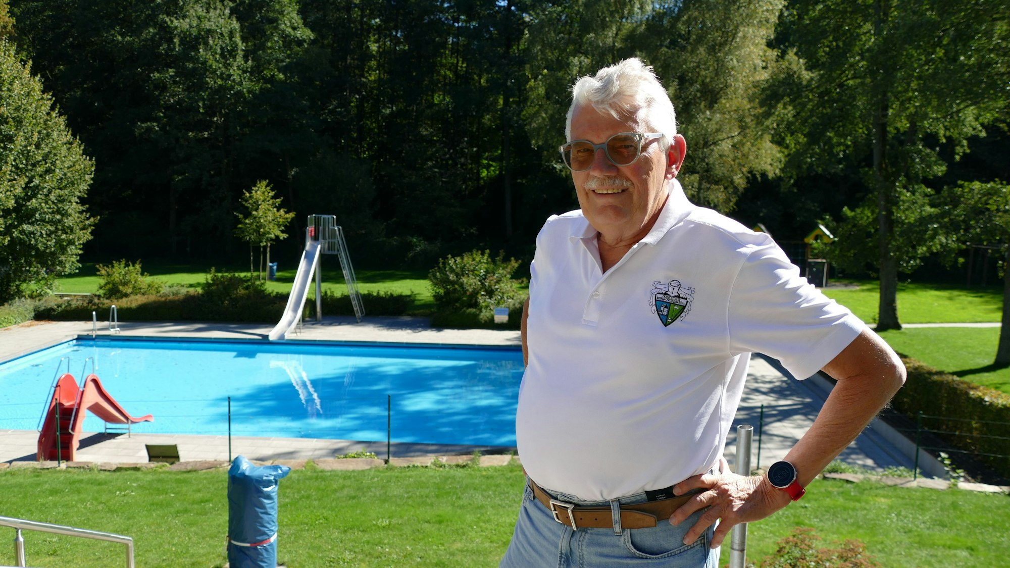 Ein Mann im Poloshirt steht in einem leeren Freibad.