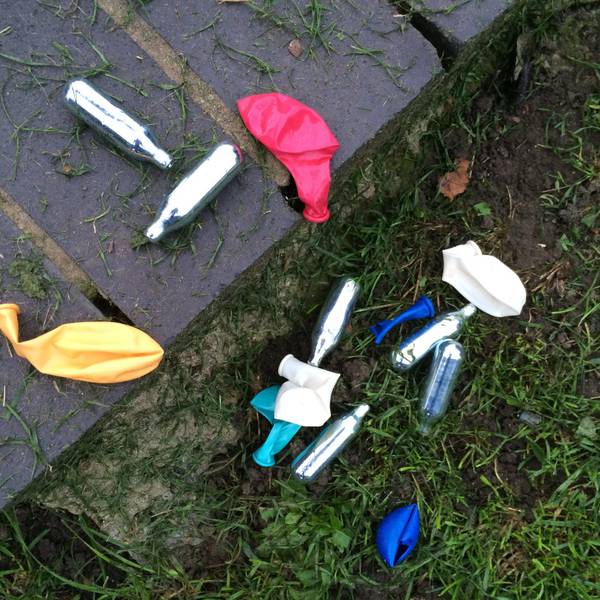 Lachgas-Kartuschen und Luftballons liegen in einem Park