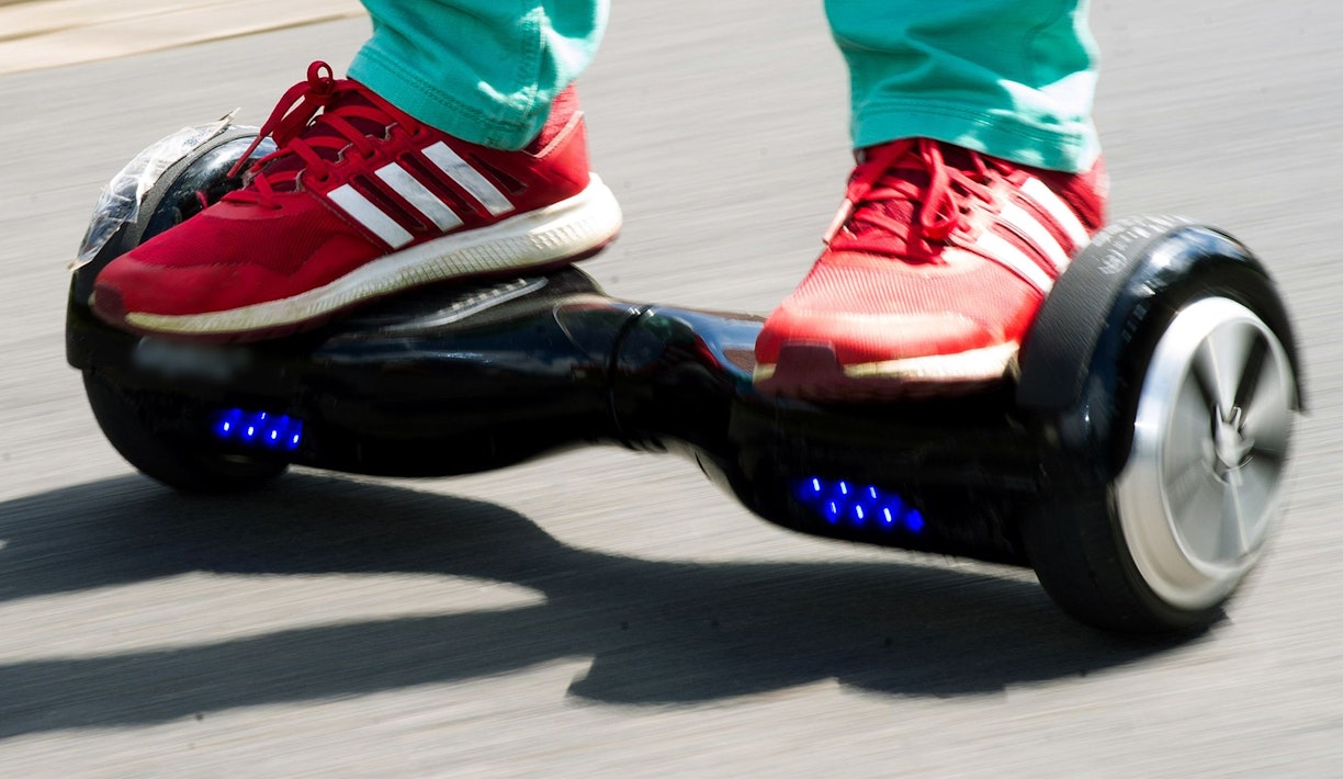 Ein Mensch rollt auf einem Hoverboard über eine Straße.