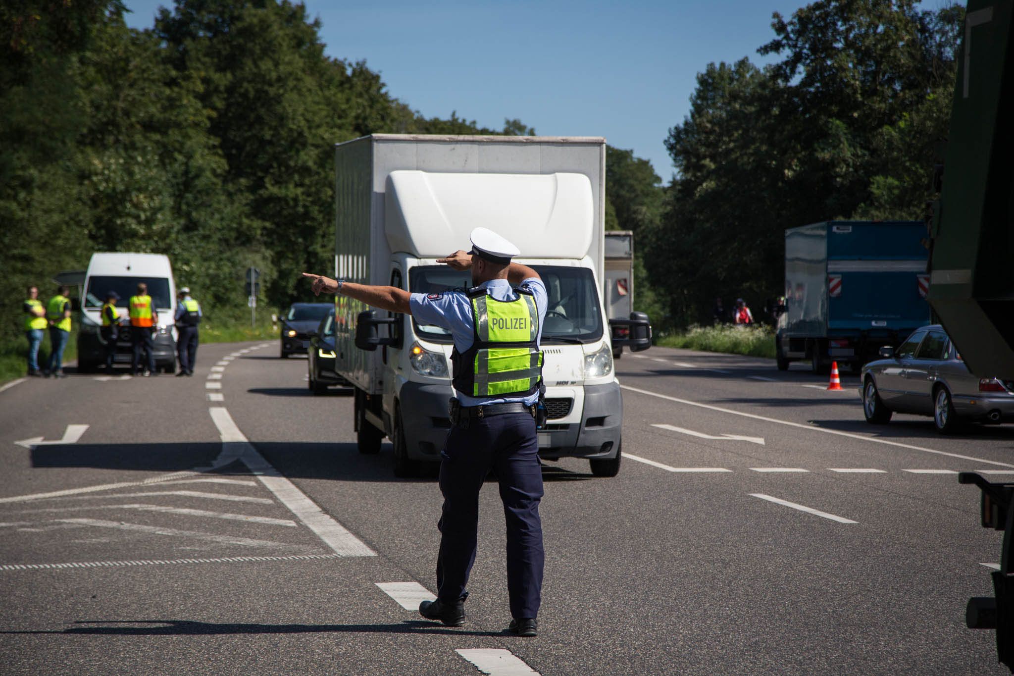Das Bild zeigt einen Polizisten, der einen Kleintransporter auf den Seitenstreifen winkt.