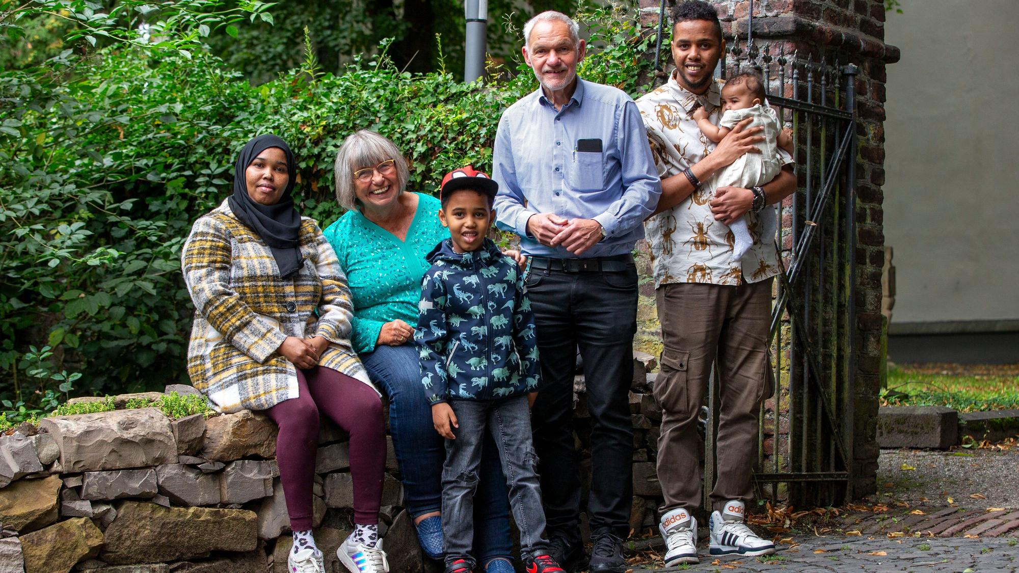 Glücklich in ihrer neuen Heimat sind Samira und Fouad A. mit ihren Kindern. Und sehr dankbar für die Hilfe von Mentorin Angelika K. und Mentor Ottmar Bongers. Alle stehen zusammen und lächeln.