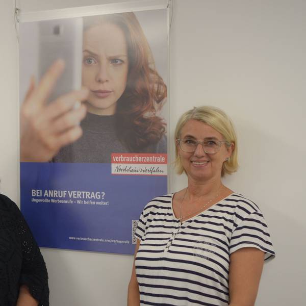 Die Leiterin der Verbraucherberatungsstelle Euskirchen, Monika Schiffer (l.), und Kriminalhauptkommissarin Eva Winkel stehen vor einem Plakat mit der Aufschrift „Bei Anruf Vertrag? Ungewollte Werbeanrufe – Wir helfen weiter!“