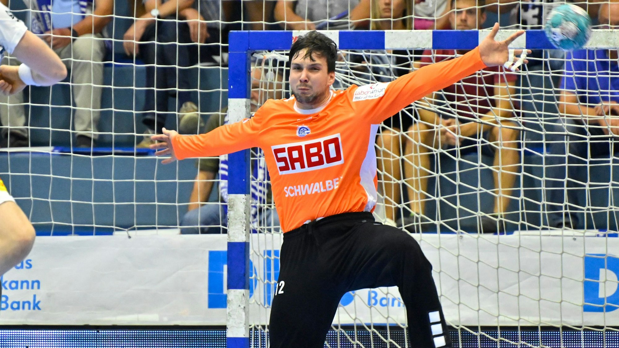 Torhüter Daniel Rebmann hat beide Arme zur Seite gestreckt, um den Ball, der aufs Tor kommt, abzuwehren.