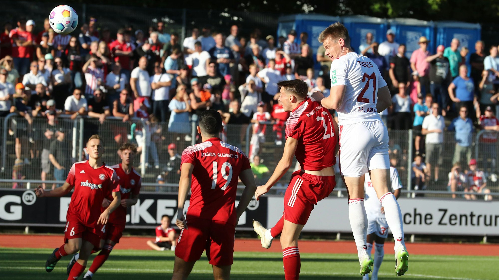 Der Fußball fliegt in Richtung linker Bildrand, während sich ein Spieler noch in der Luft befindet.