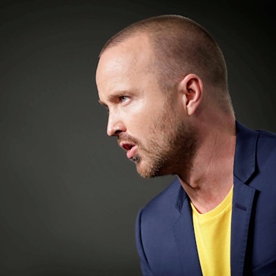 US-Schauspieler Aaron Paul ist auf einer Bühne im Anzug zu sehen.