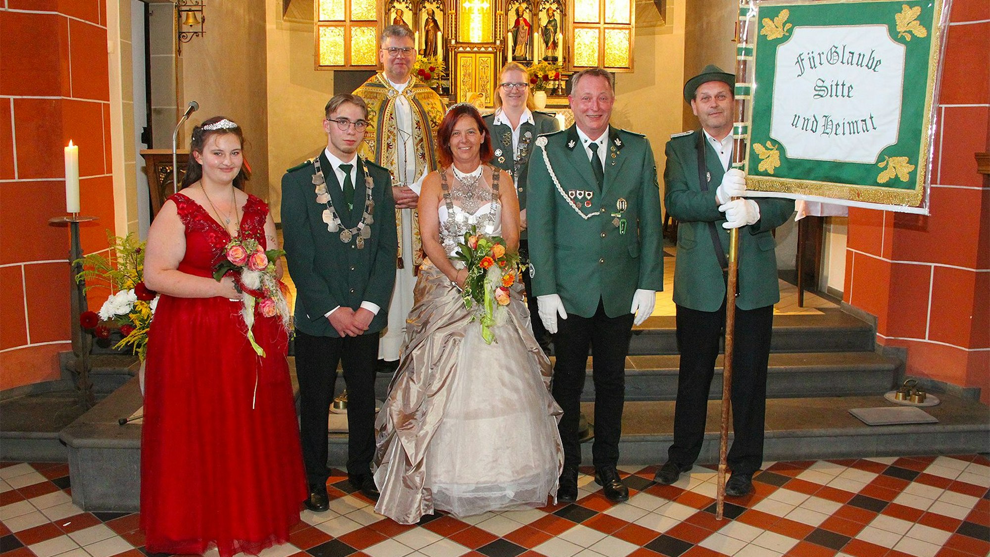 Schützen aus Rohr-Lindweiler und Königin Claudia Stern (M.) stehen in Uniform und festlicher Kleidung vor dem Altar in der Kirche.
