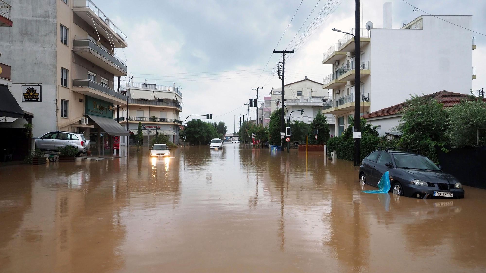 06.09.2023, Griechenland, Volos: Ein Autofahrer versucht, eine überflutete Straße nach einem Regensturm zu passieren.