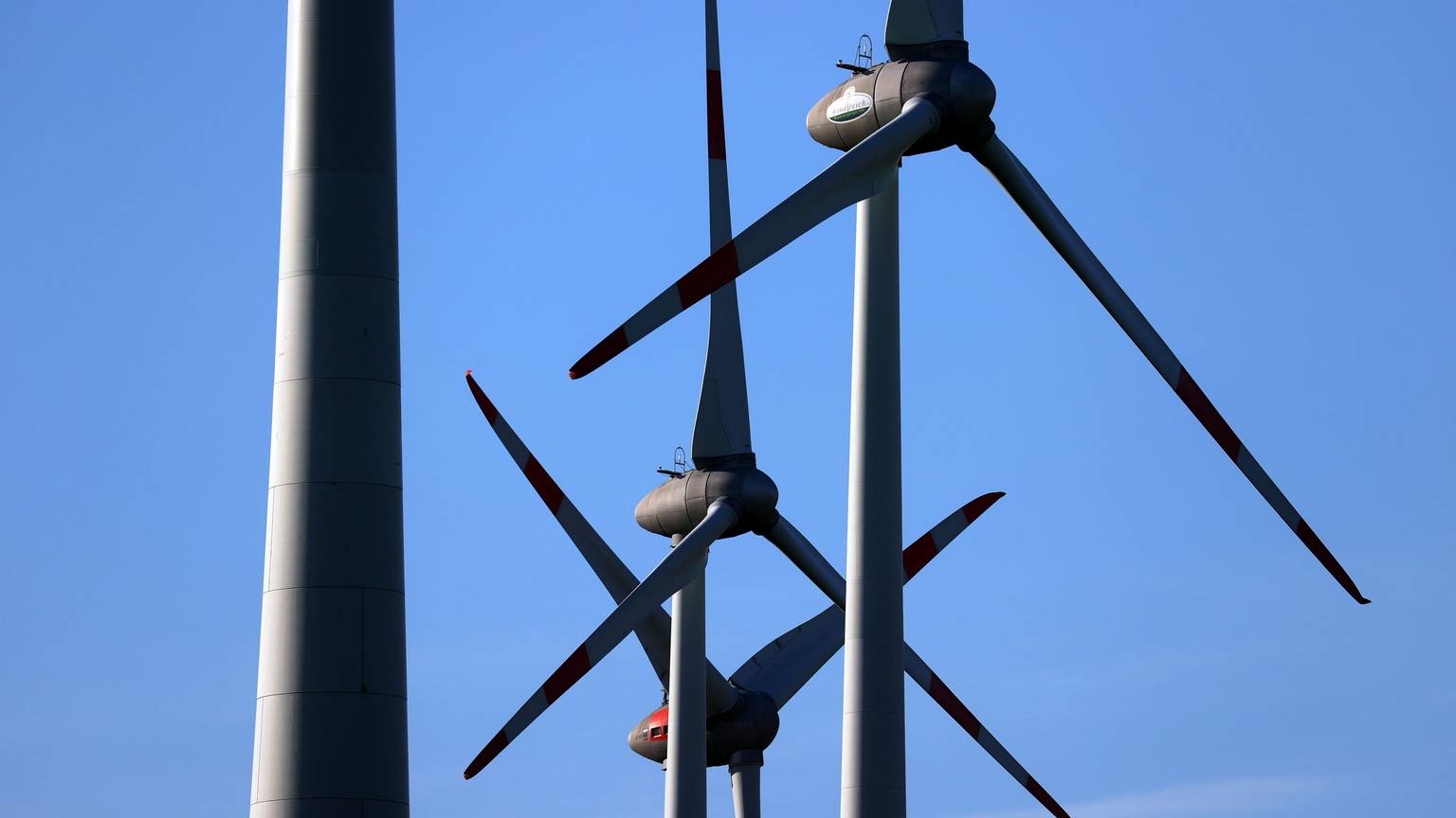 Windräder drehen sich vor blauem Himmel.
