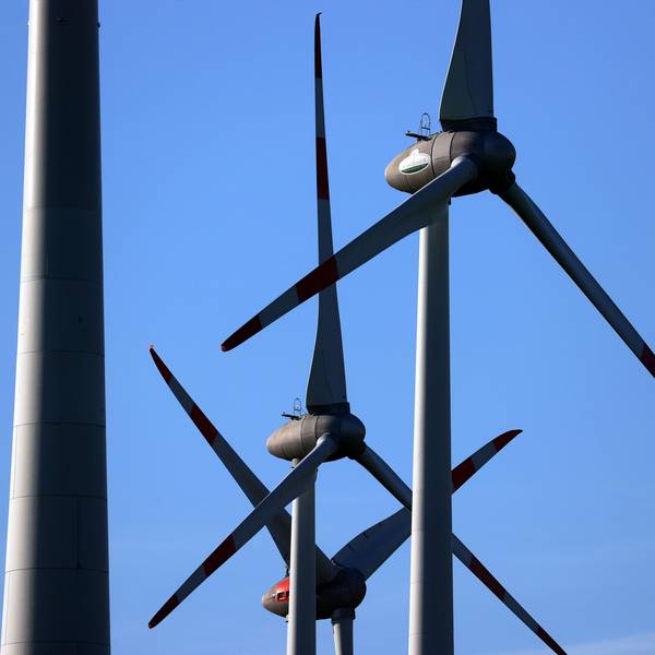 Windräder drehen sich vor blauem Himmel.