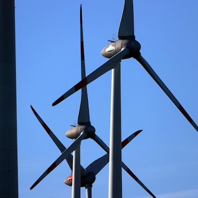 Windräder drehen sich vor blauem Himmel.