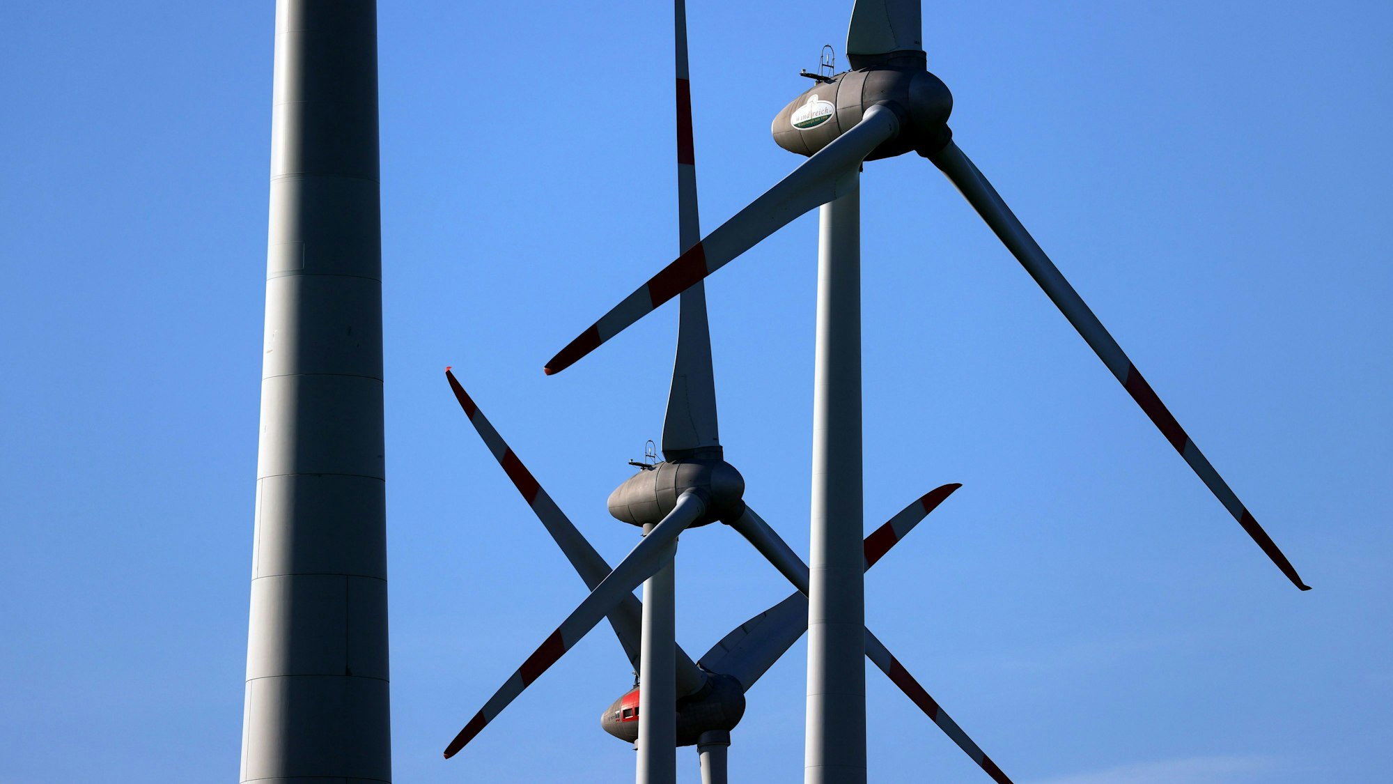 Windräder drehen sich vor blauem Himmel.