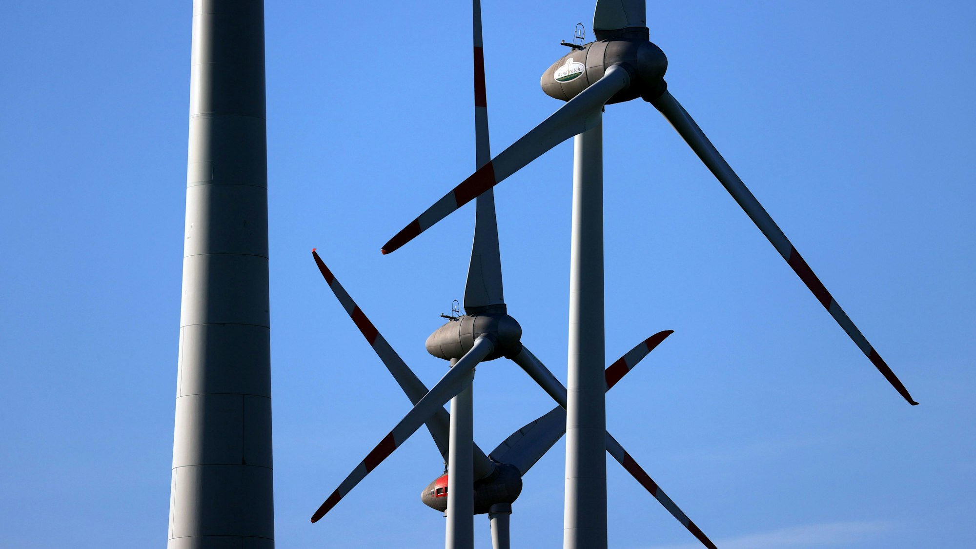 Windräder drehen sich vor blauem Himmel.
