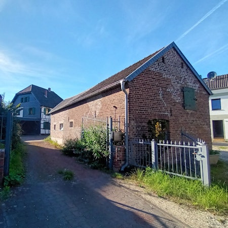 Eine Einfahrt führt zu einem Fachwerkwohnhaus