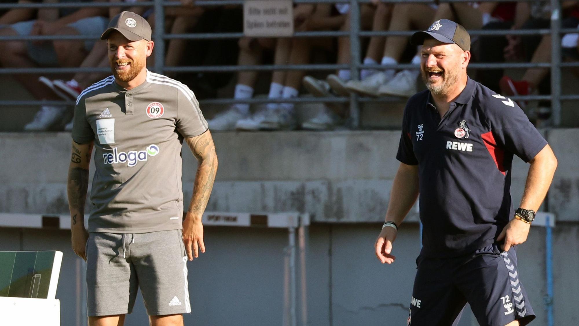 Am Spielfeldrand lachen Mike Wunderlich und Steffen Baumgart während des Spiels.