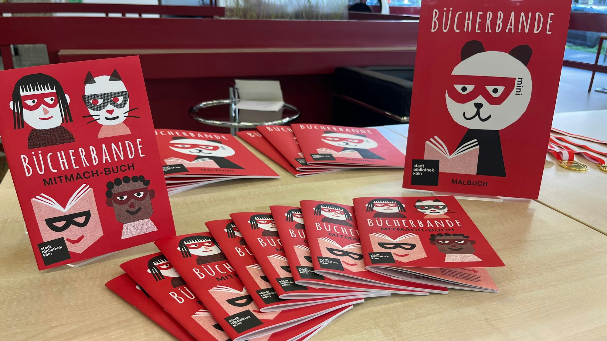 Die Mitmach-Bücher, auf denen „Bücherbande“ steht, liegen auf einem Tisch aus.