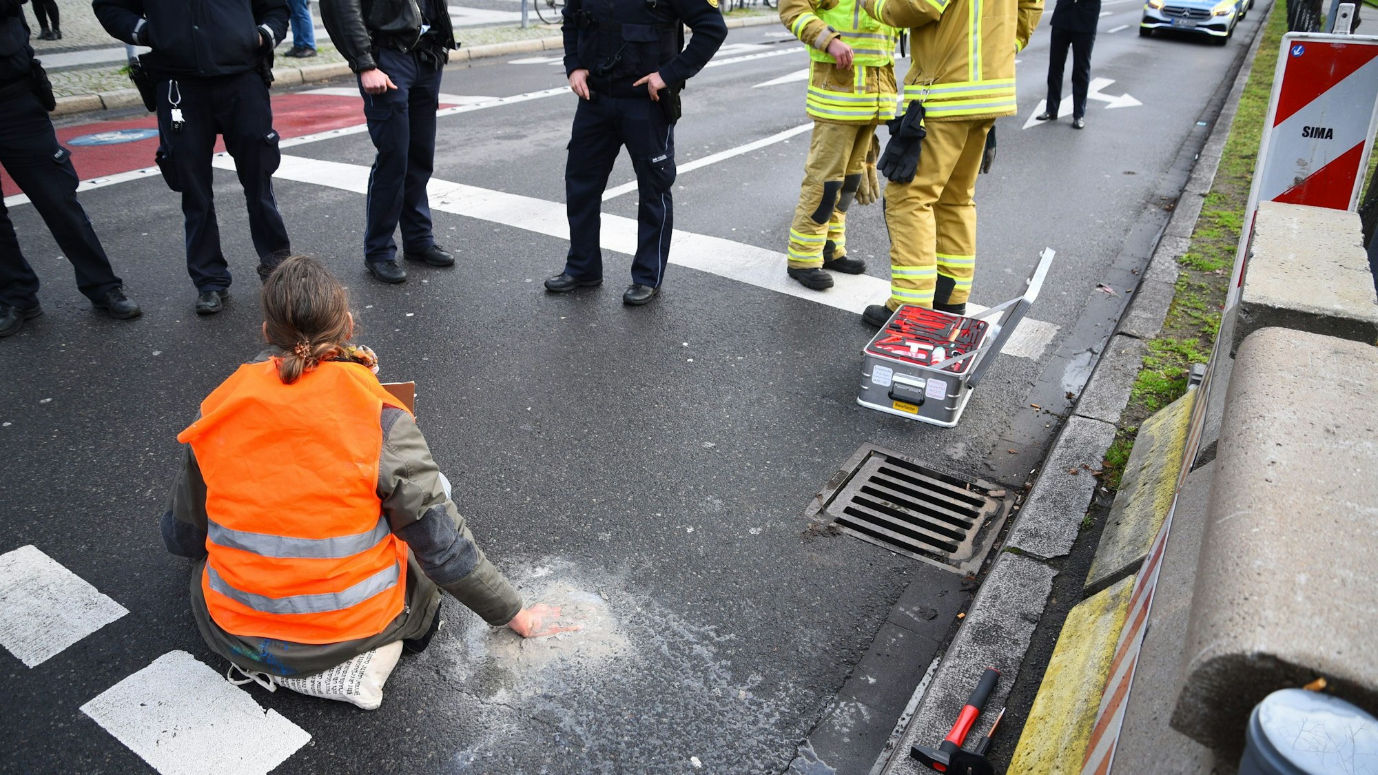 ARCHIV - 06.01.2023, Baden-Württemberg, Mannheim: Ein Aktivist der Gruppierung Letzte Generation sitzt mit einer angeklebten Hand auf der Straße. (zu dpa «Weitere Entwicklung nach dem umstrittenen Vorgehen der Polizei in Mannheim gegen Klimaaktivisten») Foto: René Priebe/dpa +++ dpa-Bildfunk +++