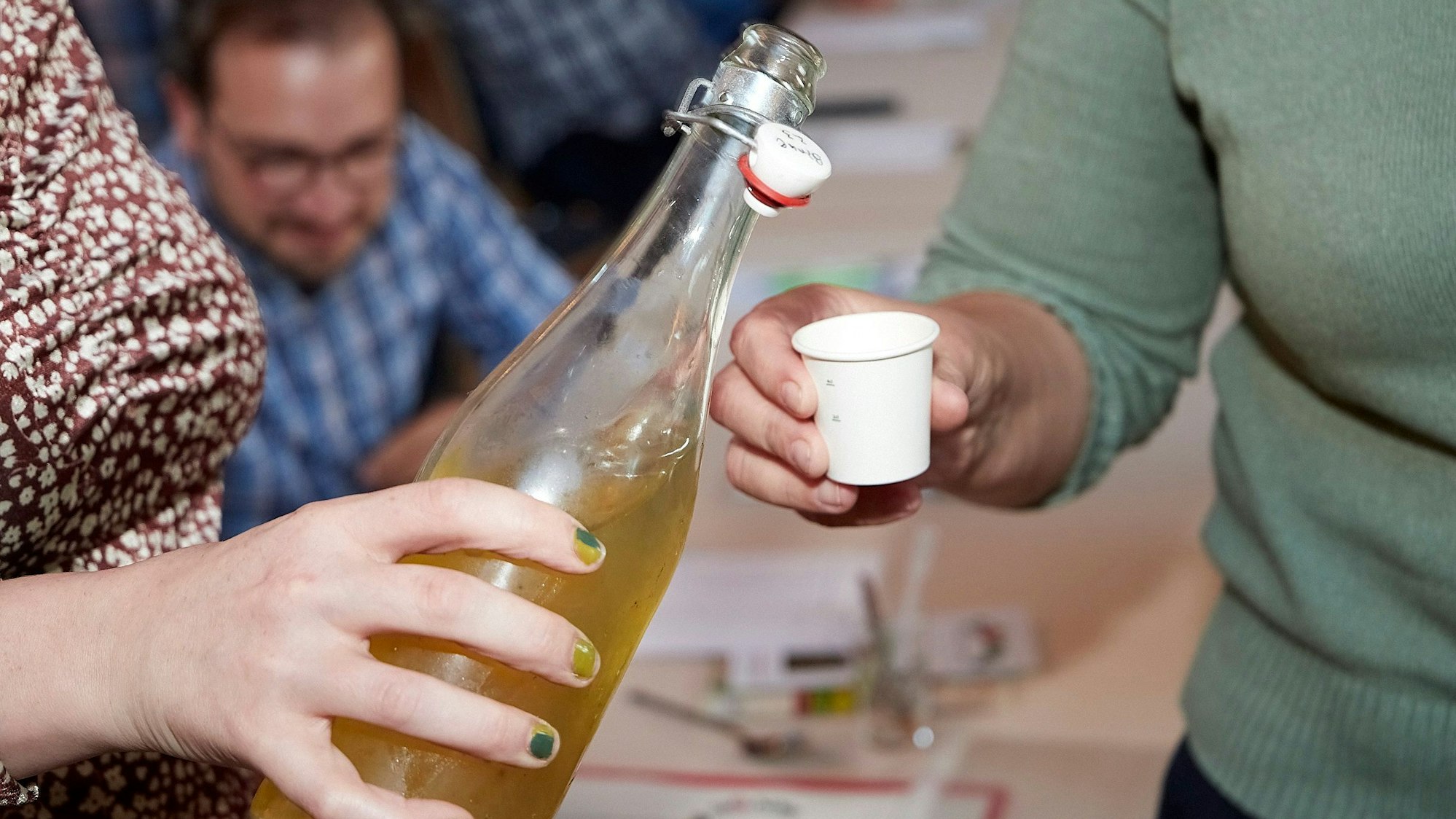 Aus einer Flasche ohne Etikett füllen Teilnehmer den Cidre zum Verkosten in ein Probierglas.