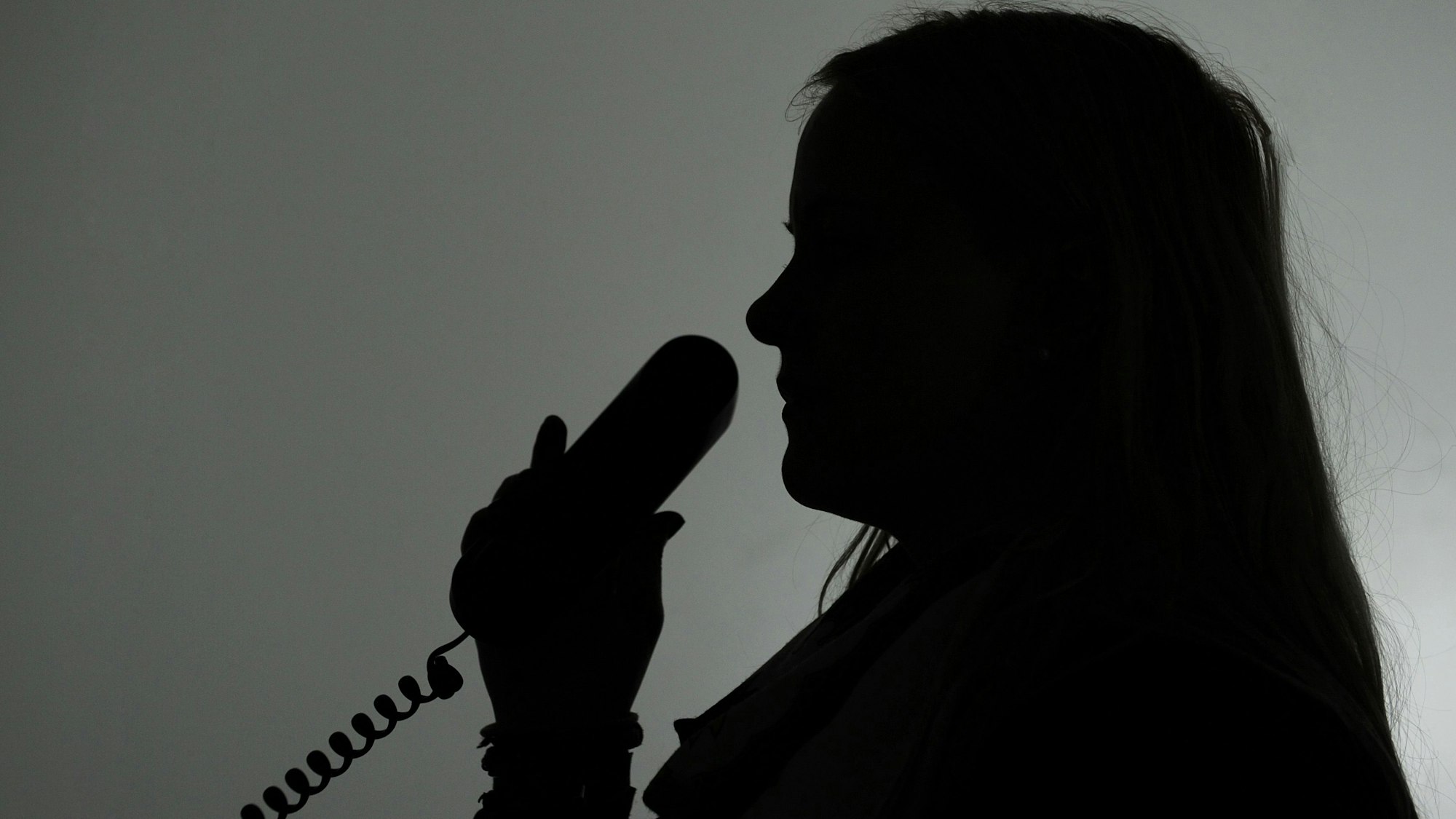 Eine Frau hält einen Telefonhörer (gestellte Aufnahme, Symbolbild).