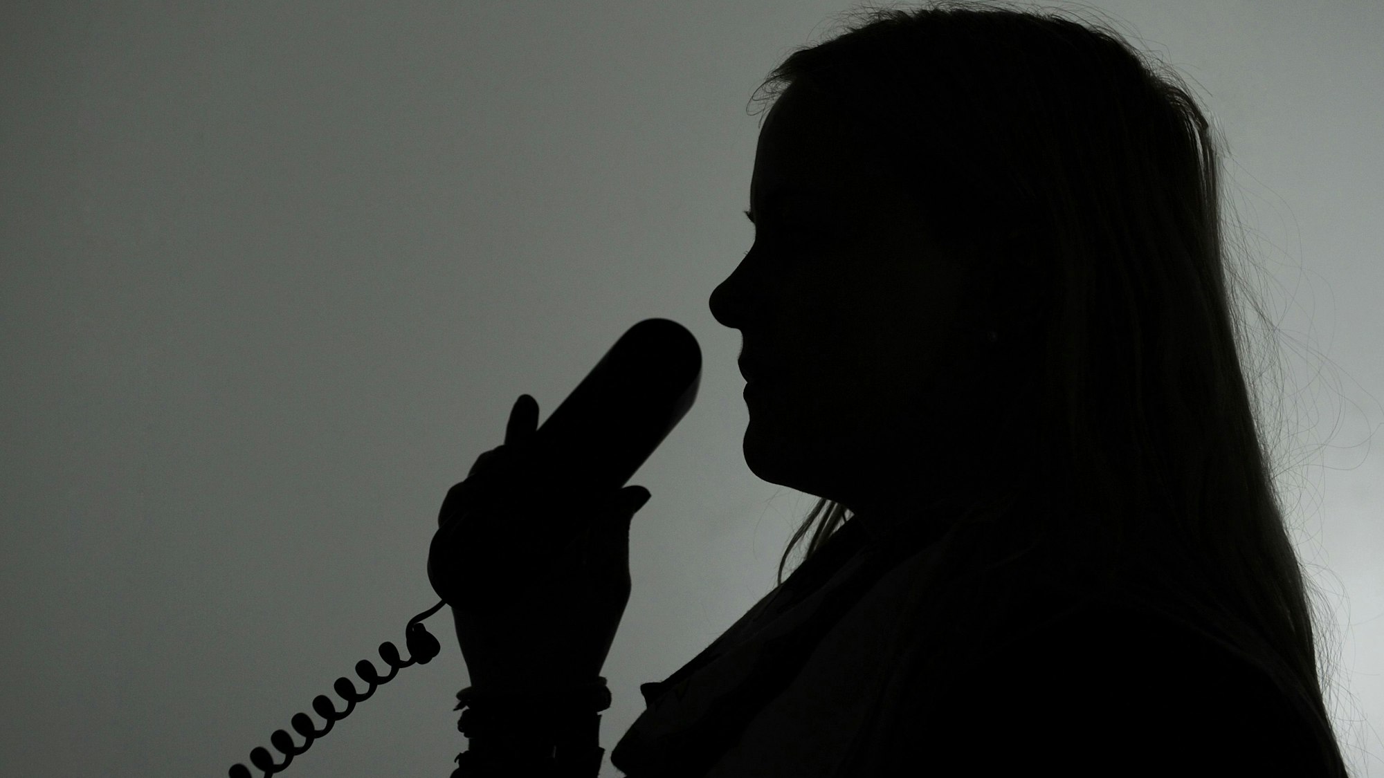 Eine Frau hält einen Telefonhörer (gestellte Aufnahme, Symbolbild).