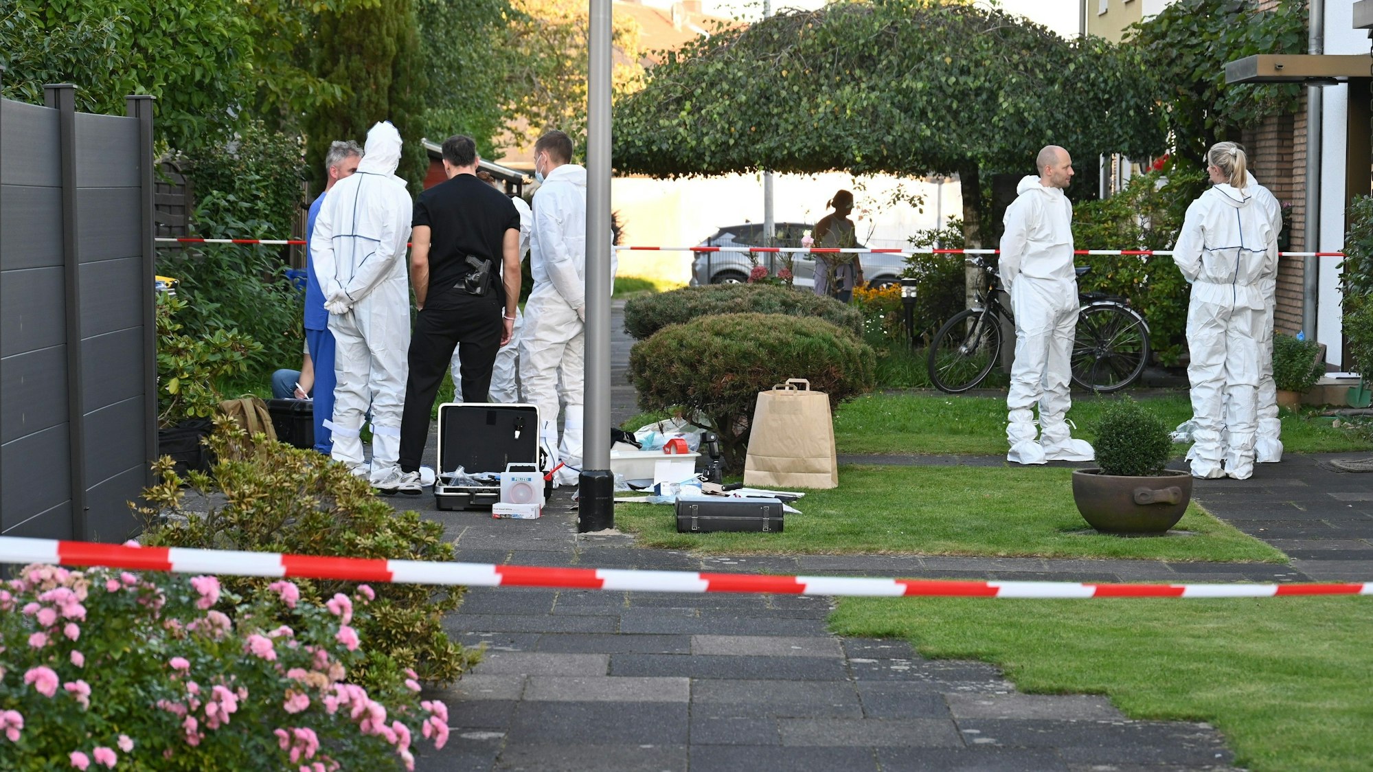 Das Bild zeigt Beamte der Mordkommission in weißen Schutzanzügen.